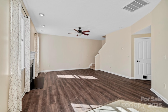 unfurnished living room featuring dark wood-style floors, a fireplace, visible vents, a ceiling fan, and stairs