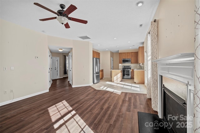 unfurnished living room featuring light wood finished floors, baseboards, visible vents, and a high end fireplace