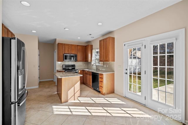 kitchen with light stone counters, light tile patterned floors, stainless steel appliances, backsplash, and a sink