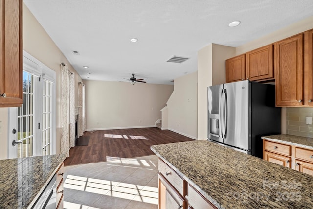 kitchen featuring stainless steel refrigerator with ice dispenser, tasteful backsplash, visible vents, dark stone countertops, and tile patterned flooring