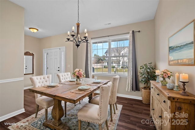 dining area featuring dark wood-type flooring, a notable chandelier, and baseboards