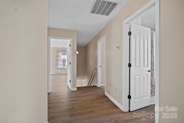 hall featuring baseboards, visible vents, an upstairs landing, and wood finished floors