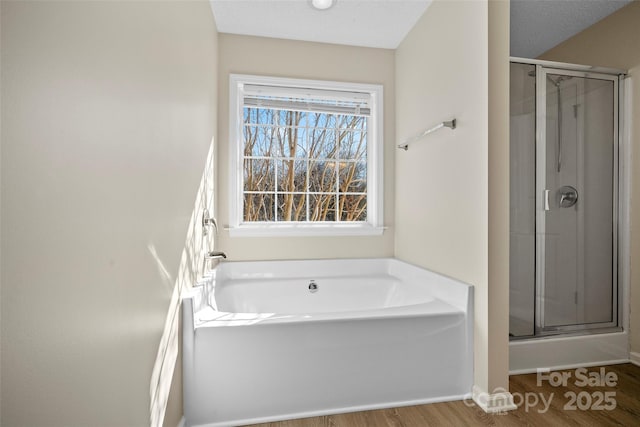 bathroom featuring a stall shower, a bath, and wood finished floors