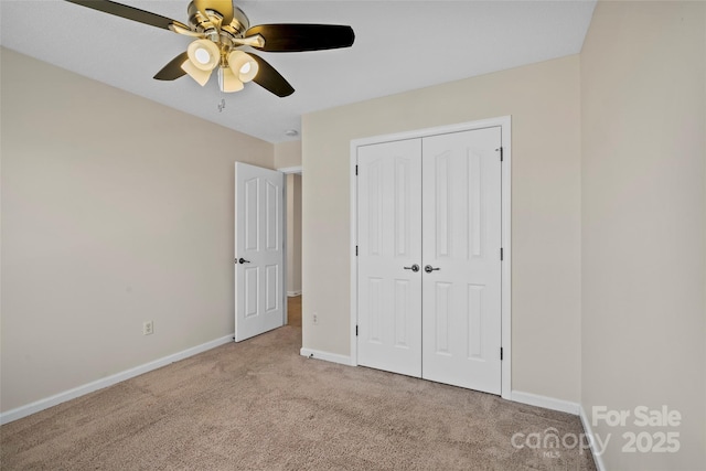 unfurnished bedroom featuring carpet, baseboards, ceiling fan, and a closet