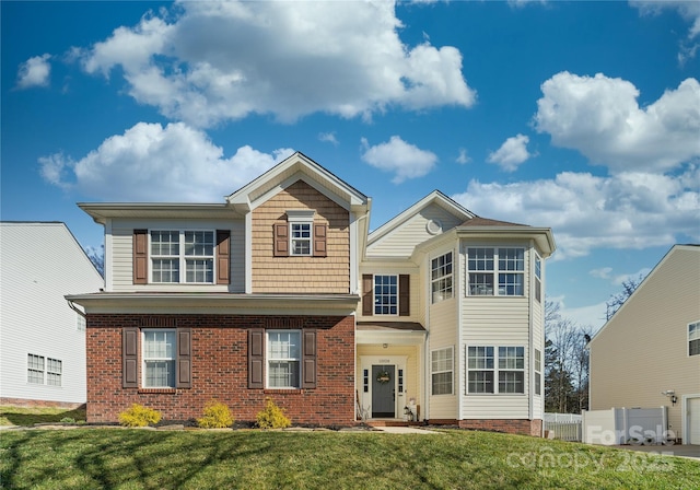 traditional-style home with a front lawn, fence, and brick siding