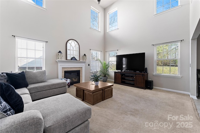 living area with a glass covered fireplace, light carpet, and baseboards