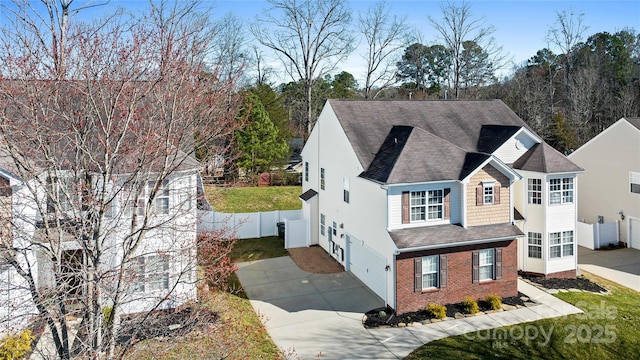 exterior space with fence, concrete driveway, and brick siding