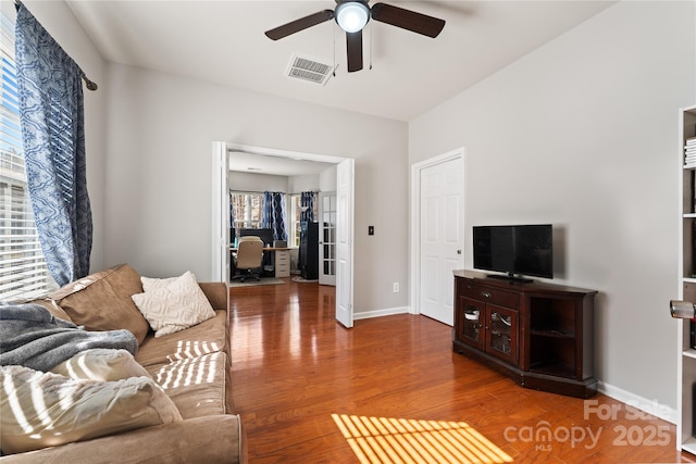 living room with a ceiling fan, baseboards, visible vents, and wood finished floors