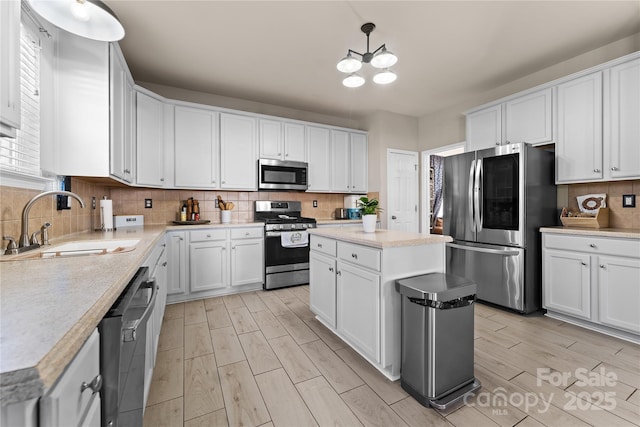 kitchen with appliances with stainless steel finishes, a sink, wood tiled floor, light countertops, and backsplash