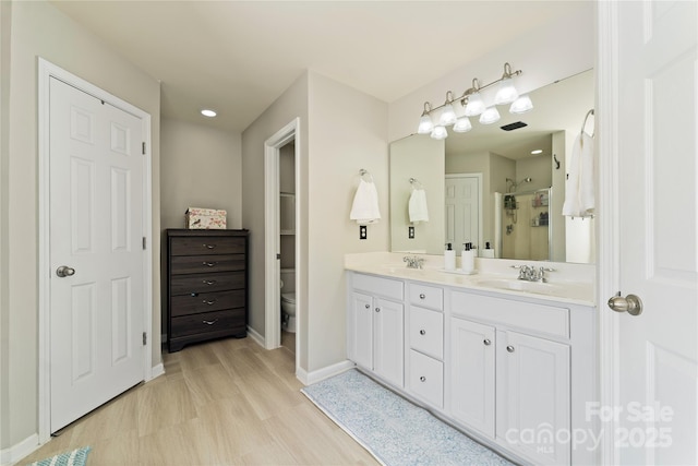 bathroom with double vanity, a sink, toilet, and a shower stall