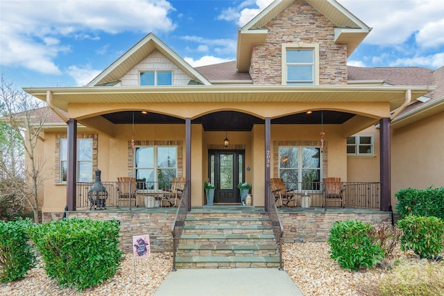 doorway to property with stone siding, covered porch, and stucco siding