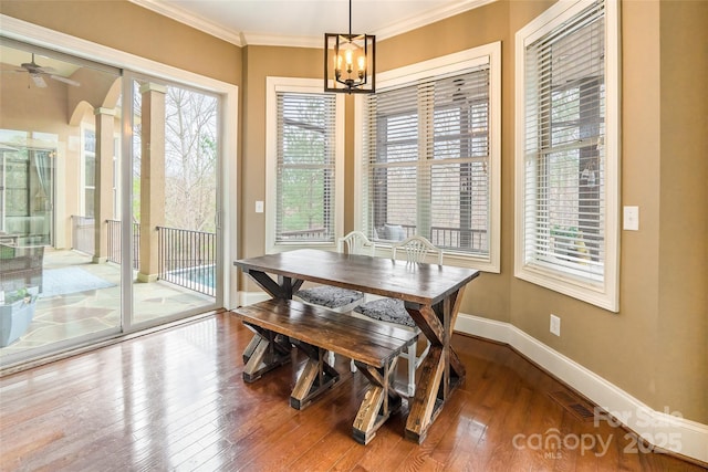 dining room with arched walkways, hardwood / wood-style flooring, visible vents, baseboards, and crown molding