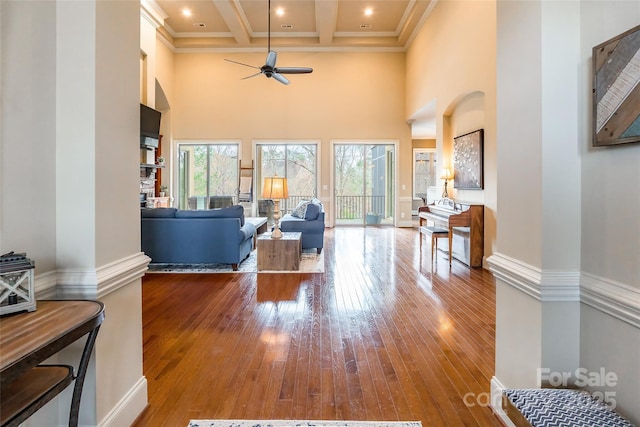 living area featuring a high ceiling, beamed ceiling, coffered ceiling, and hardwood / wood-style flooring