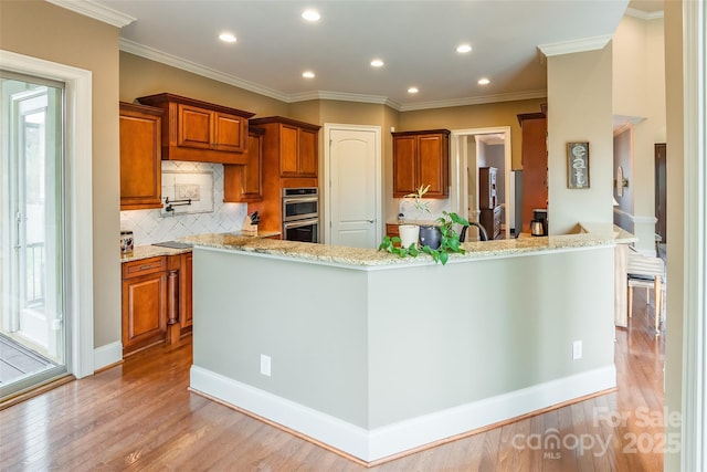 kitchen with double oven, light wood finished floors, light stone countertops, and brown cabinets