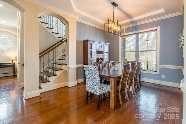 dining space featuring a tray ceiling, stairway, hardwood / wood-style floors, and a notable chandelier