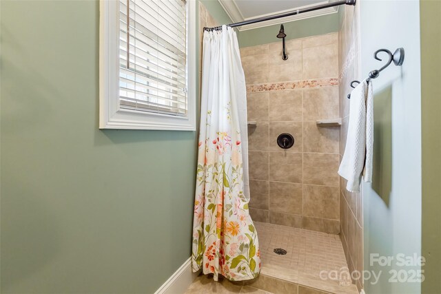 bathroom featuring tiled shower and baseboards