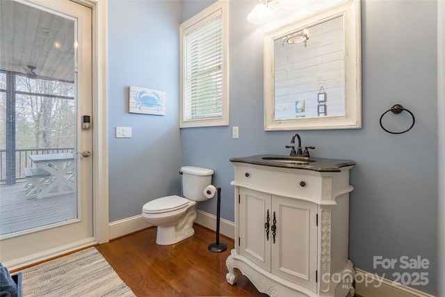 bathroom with toilet, baseboards, wood finished floors, and vanity