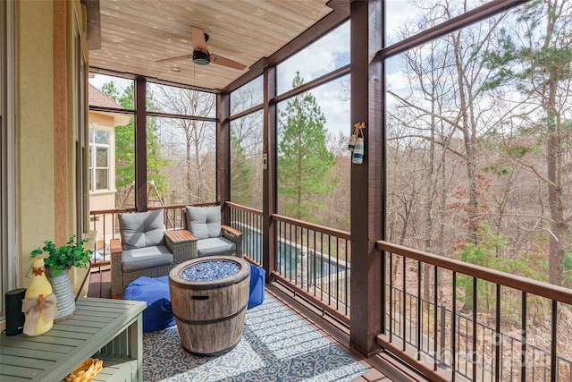 sunroom featuring wooden ceiling and a ceiling fan