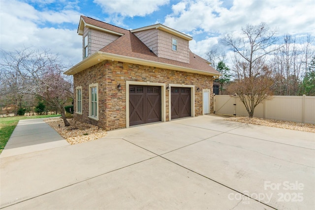 view of property exterior featuring a garage, stone siding, fence, and concrete driveway