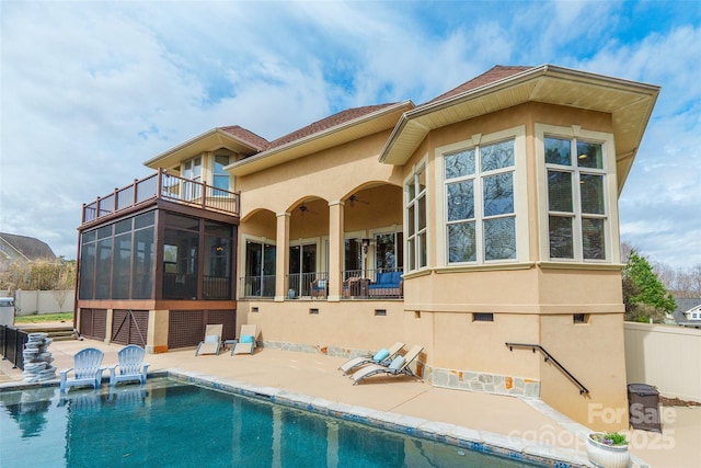 rear view of house featuring a balcony, a patio area, a sunroom, and stucco siding