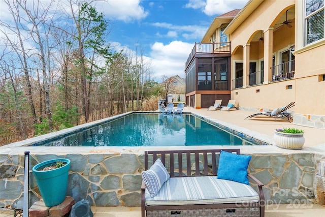 pool with a sunroom, a patio area, and a ceiling fan