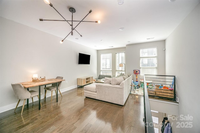 living room featuring a chandelier, baseboards, and wood finished floors