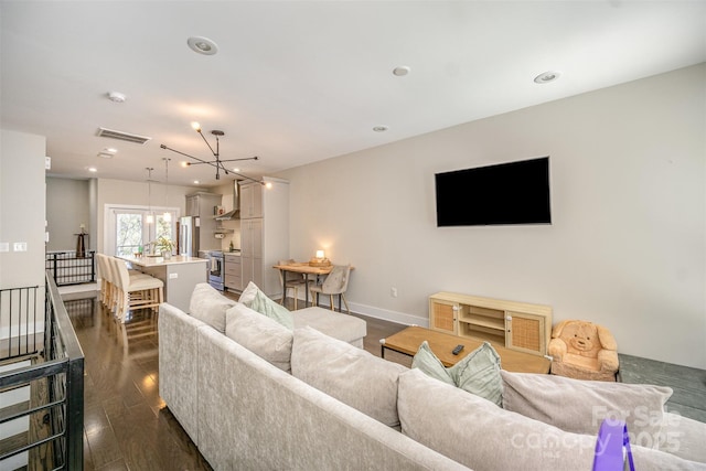 living area with visible vents, a notable chandelier, dark wood finished floors, recessed lighting, and baseboards