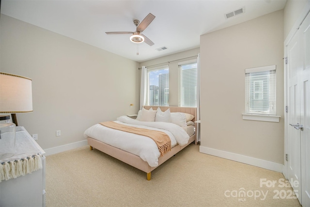 bedroom featuring ceiling fan, baseboards, visible vents, and light carpet