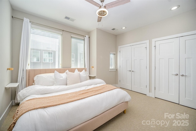 carpeted bedroom with visible vents, recessed lighting, and two closets