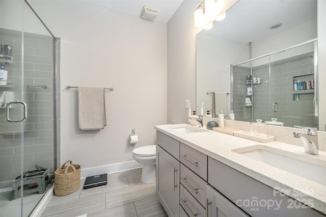 full bathroom featuring visible vents, toilet, a sink, a shower stall, and double vanity