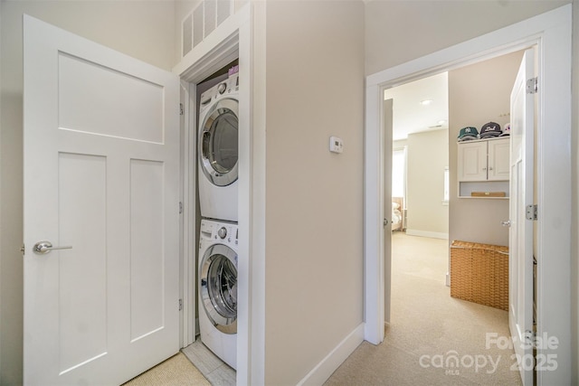 laundry room with visible vents, light carpet, stacked washer and clothes dryer, baseboards, and laundry area