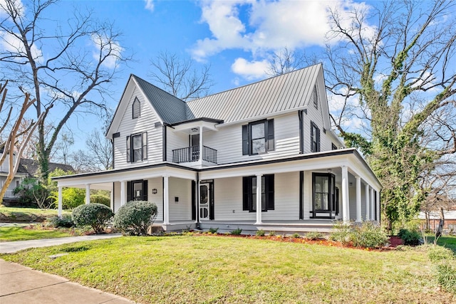 view of front of home with a balcony, covered porch, metal roof, and a front lawn