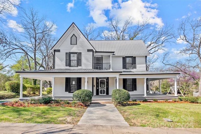 country-style home featuring a porch, a standing seam roof, metal roof, a balcony, and a front lawn