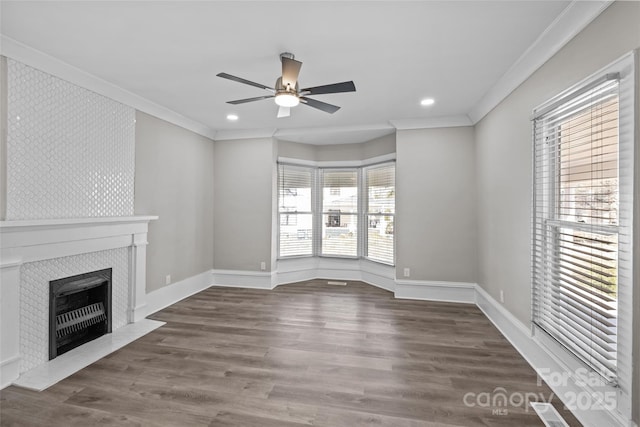 unfurnished living room with baseboards, a tiled fireplace, ceiling fan, ornamental molding, and wood finished floors