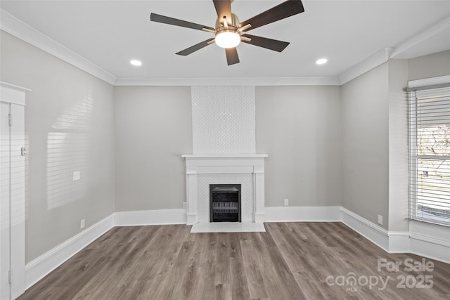 unfurnished living room featuring baseboards, a tiled fireplace, wood finished floors, and crown molding