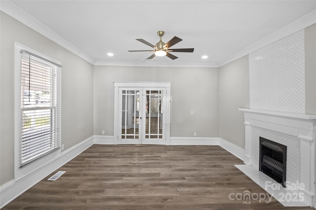 unfurnished living room with visible vents, a ceiling fan, a tile fireplace, dark wood-style floors, and crown molding