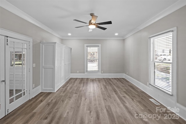 spare room featuring ornamental molding, wood finished floors, visible vents, and baseboards