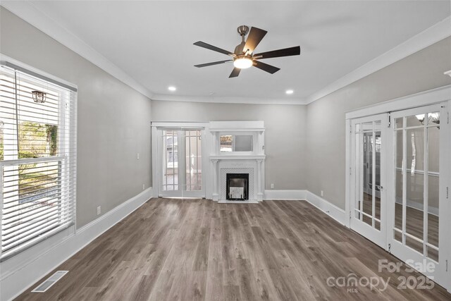 unfurnished living room featuring wood finished floors, a fireplace with flush hearth, visible vents, baseboards, and french doors