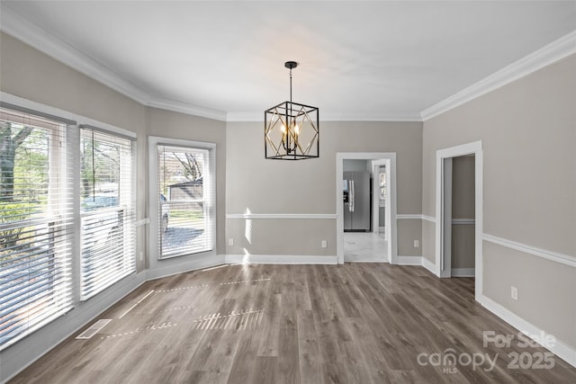 unfurnished dining area featuring baseboards, crown molding, visible vents, and wood finished floors