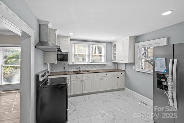 kitchen featuring dark countertops, marble finish floor, stainless steel appliances, wall chimney range hood, and a sink