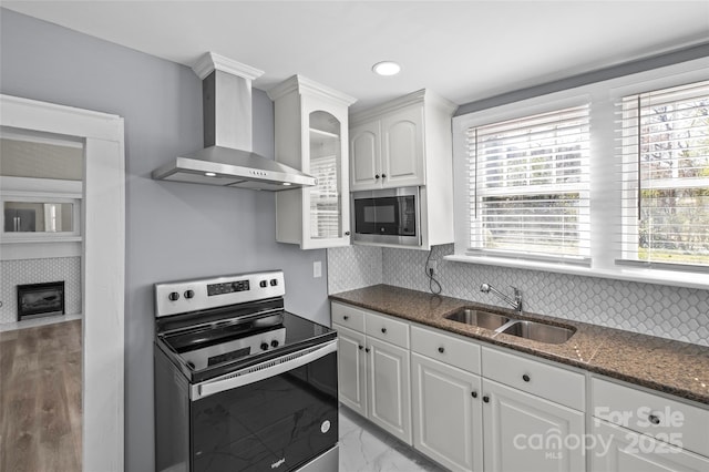 kitchen featuring wall chimney range hood, a wealth of natural light, stainless steel appliances, and a sink