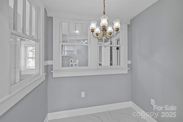 dining area featuring marble finish floor, baseboards, and an inviting chandelier