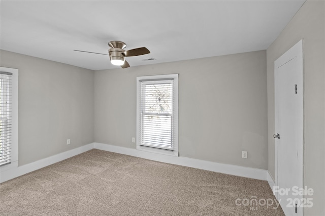 carpeted empty room featuring baseboards, visible vents, and a ceiling fan