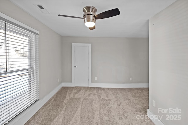 unfurnished room featuring carpet floors, baseboards, visible vents, and ceiling fan