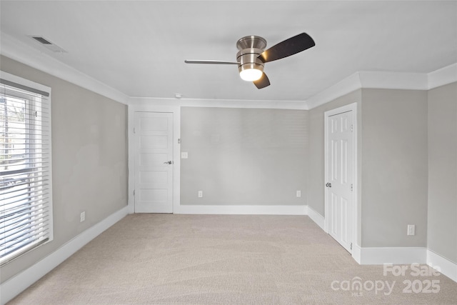 spare room featuring visible vents, ornamental molding, carpet flooring, and a wealth of natural light