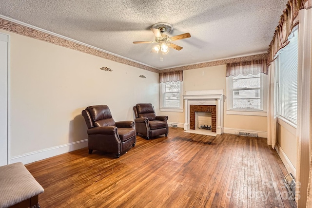 living area with ceiling fan, a textured ceiling, visible vents, baseboards, and hardwood / wood-style floors