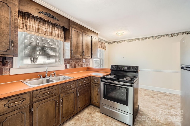 kitchen featuring stainless steel appliances, light countertops, dark brown cabinetry, a sink, and baseboards