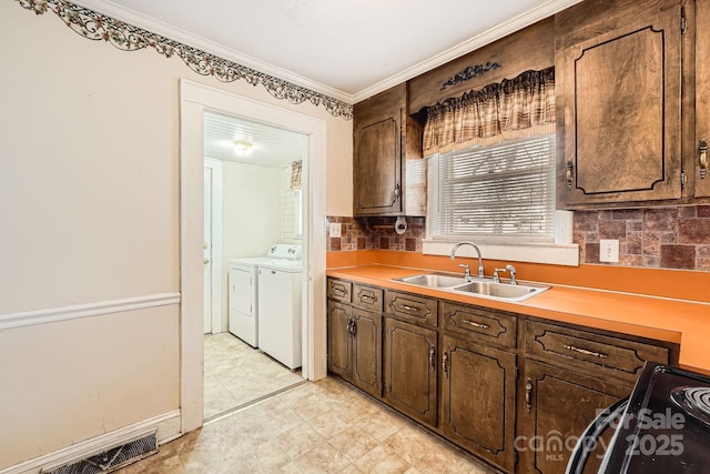 kitchen featuring black electric range, a sink, backsplash, and separate washer and dryer