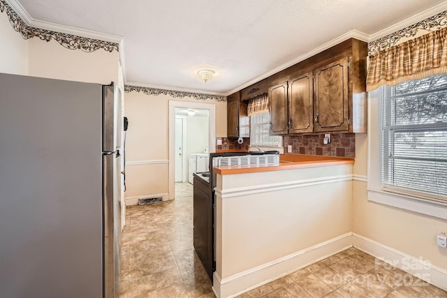 kitchen with light countertops, decorative backsplash, freestanding refrigerator, a peninsula, and baseboards