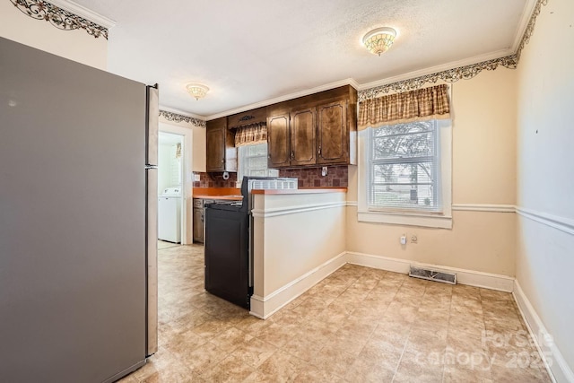 kitchen featuring tasteful backsplash, visible vents, freestanding refrigerator, dark brown cabinets, and baseboards